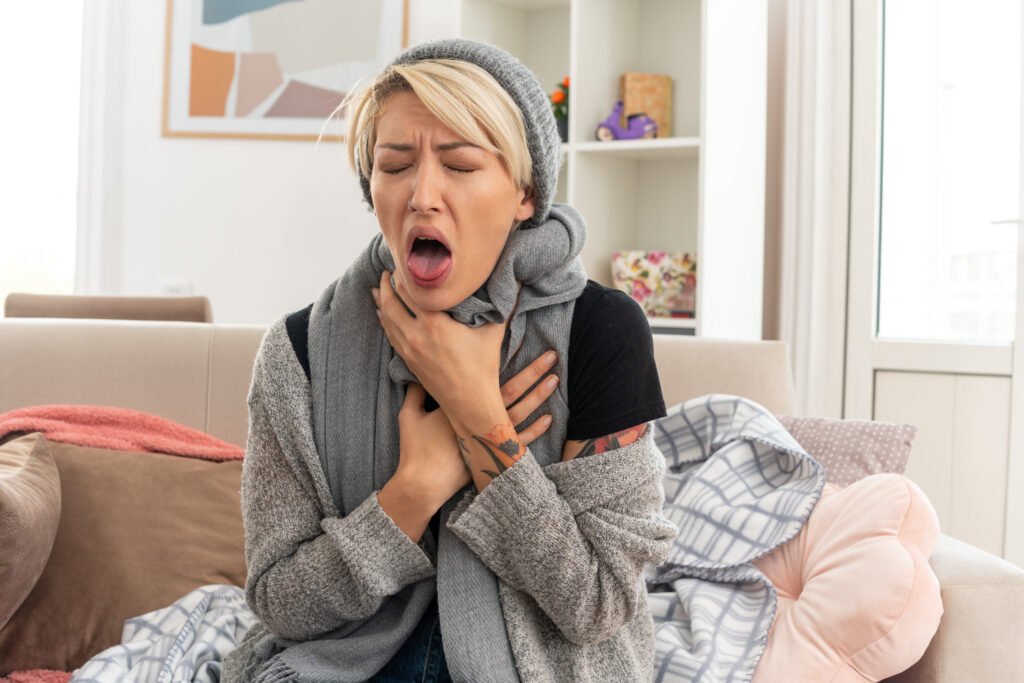 coughing woman sitting on couch ay home