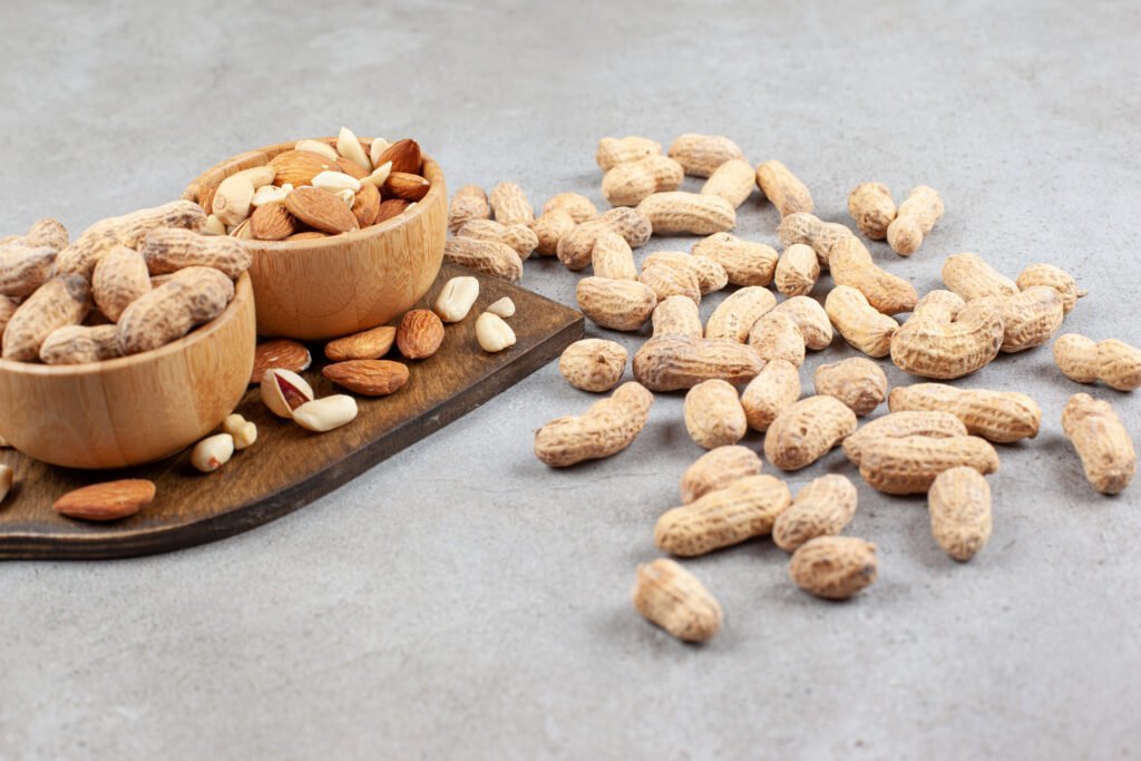Assortment of peanuts and tree nuts in bowls on a wooden board, illustrating potential allergy triggers